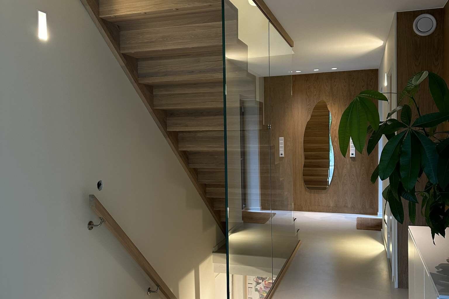 Eiketrapp med lang glassvegg i moderne bolig.