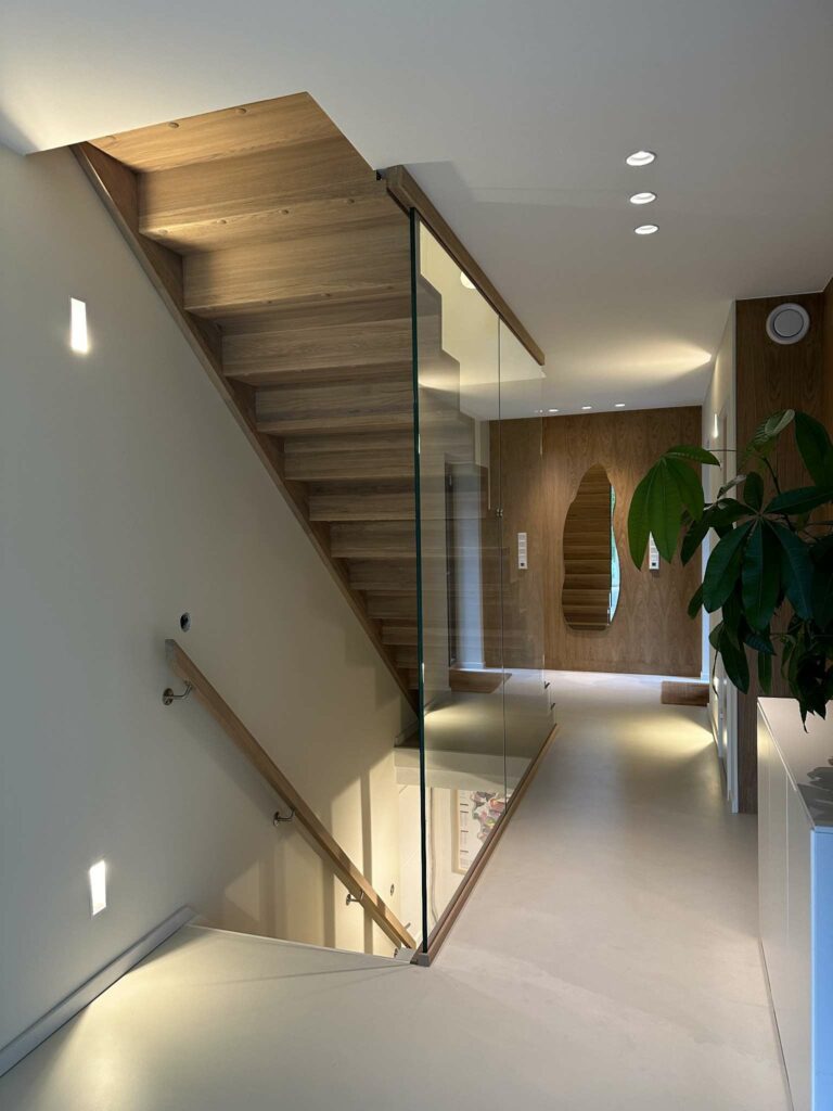 Eiketrapp med lang glassvegg i moderne bolig.